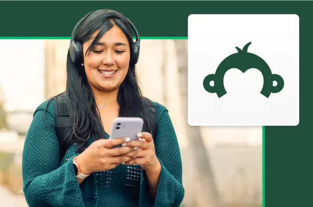 SurveyMonkey Goldie 로고 옆에서 헤드폰을 착용하고 휴대폰 화면을 보면서 미소 짓는 여성